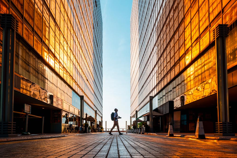 Person med kamera bland höga byggnader i solnedgång